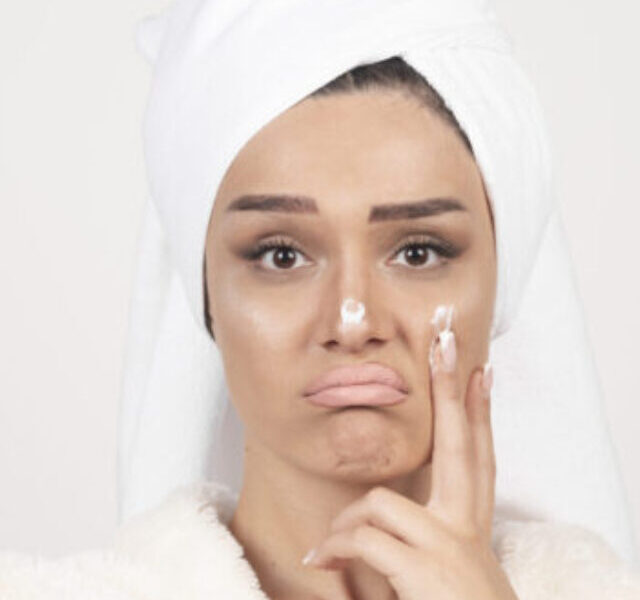 Beautiful young woman in a white bathrobe posing on a white wall